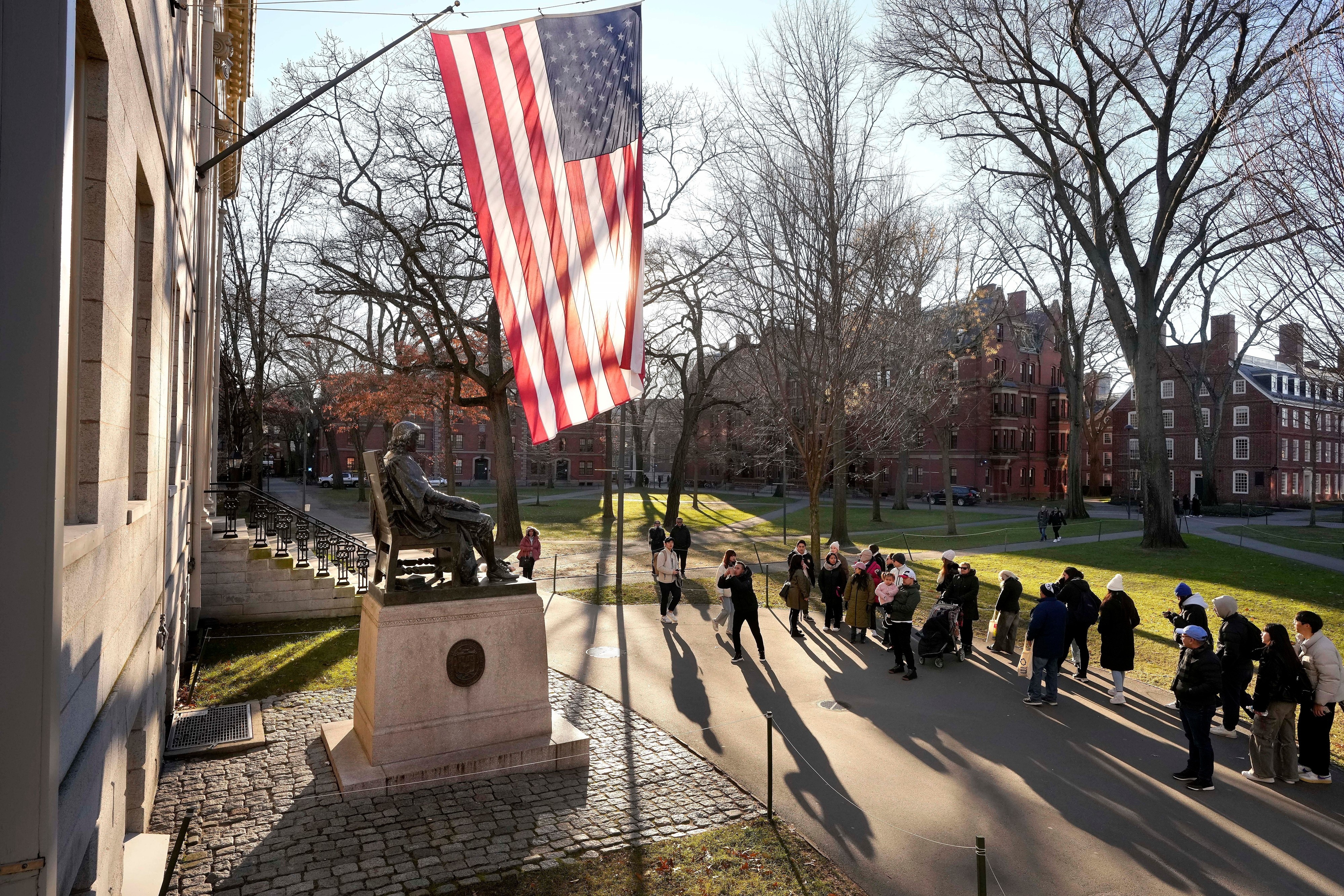 FILE - People take photos near a John Harvard statue, left, on the Harvard University campus, Jan. 2, 2024, in Cambridge, Mass.
